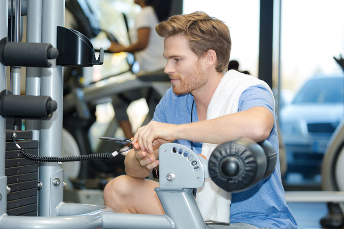 Un jeune sportif règle sa machine de fitness avant de commencer sa séance