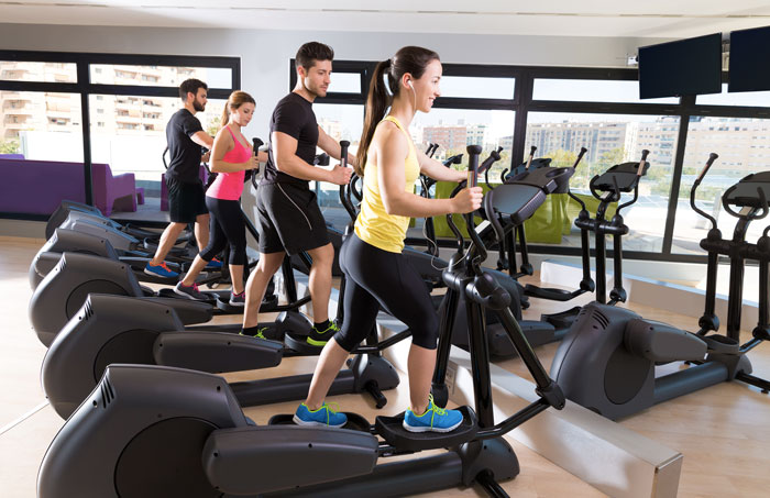 Des sportifs en pleine séance de velo elliptique dans une salle de gym